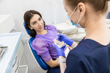 Dentistry concept. Professional dental services and modern equipment without pain. The doctor demonstrates to the patient how to properly brush the teeth