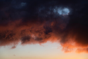 Dramatic sunset skies with orange and black clouds and a plane flying