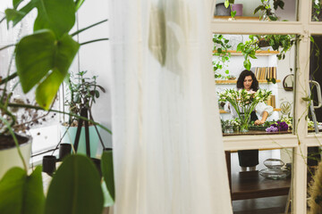 Attractive young woman florist is working in a flower shop.