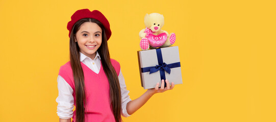 Child girl gift. happy teen girl in french beret hold toy present and gift box on yellow background, gift. Kid girl with gift, horizontal poster. Banner header with copy space.