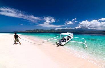 Man moors anchored traditional boat on the tropical beach