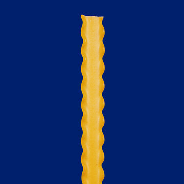 Close up still life raw reginette pasta with ruffled edges on blue background
