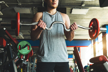 Young active muscular man performs exercises with a barbell in the gym. Power training