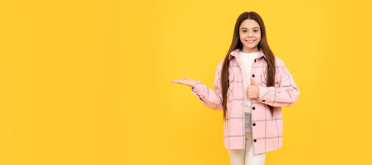 happy child girl wear pink checkered shirt presenting product, copy space, sale. Child face, horizontal poster, teenager girl isolated portrait, banner with copy space.