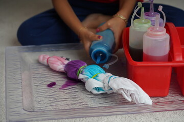 Little kid enjoying making a craft, using different colour ink to paint a tie-dyed cloth. Kids arts...