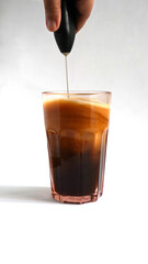 frothing milk and coffee to mixed them good, white background. edited using photo manipulation software