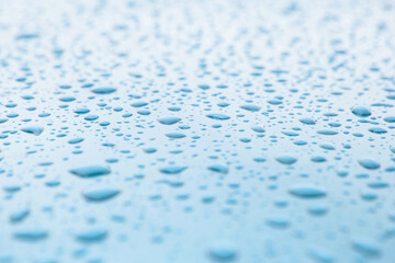 close up of small drops of rainwater or condensation on a reflective blue mettalic surface. Freshness texture background