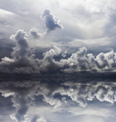 Perfect reflection of a dramatic sky landscape with clouds and sun light on the water surface.
