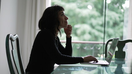 A pensive hispanic girl in front of laptop thinking. Thoughtful South American woman studying using computer2