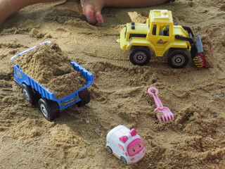 Transportation toys played by a boy in the beach. Heave vehicle toys on the beach