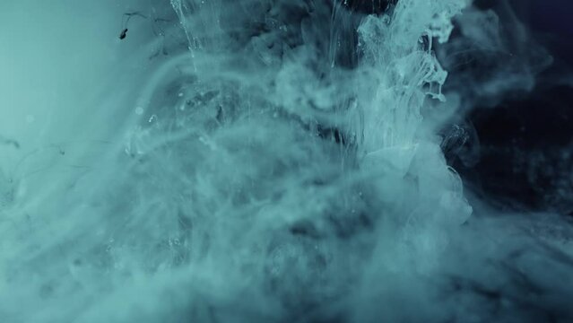 Blue cosmic nebula falling underwater against black screen - paint ink effect