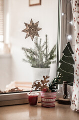 Window decorated with a garland, wooden Christmas tree and the star.