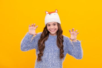 happy kid long hair in knitted hat on yellow background, winter clothing