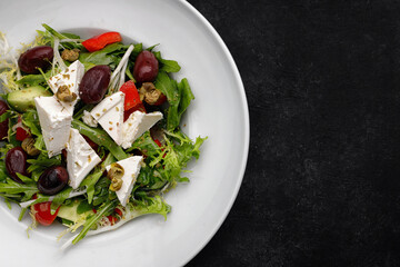 Greek salad on a plate, on a dark background