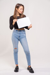 Beautiful brown-haired girl holding a sheet of paper with a copy space. The model is dressed in a black diver and blue jeans