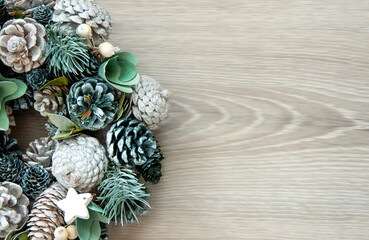 Christmas background - a wreath of cones and branches on a wooden background