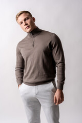 Portrait of an attractive blond german model with a brown sweater on a white background, looking at the camera