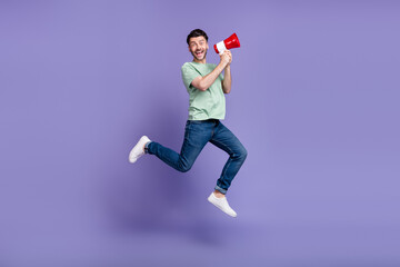 Full size photo of handsome young man jumping hold megaphone excited dressed stylish gray garment...