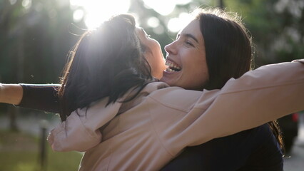 Two happy female best friends hugging each other. Women embrace reunion outdoors at park2