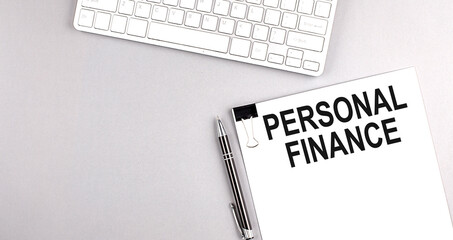 PERSONAL FINANCE text on paper with keyboard on grey background