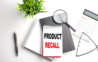 Text PRODUCT RECALL on notebook with office tools on white background