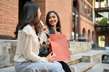 Asian female recommending the credit card for shopping to her friend