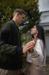 Man and a woman hold hands selectively focus on their hands. Hands in focus. Young couple in out of focus. Concept: date, couple. dating, dating app, singles, healthy attitudes