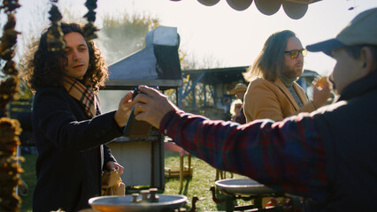 Senior farmer gives eco bag with goods to man. He contactless pays for purchases using smartphone. Weekend shopping at local farmers market outdoors. Vegetarian and organic food. Agriculture.