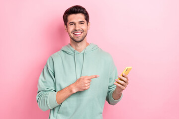 Photo of young positive marketer guy student hold new smartphone much function nice mechanics finger pointing device ad isolated on pink color background