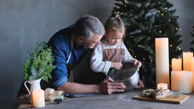 a loving father and his little daughter are cooking Christmas treats together at the table