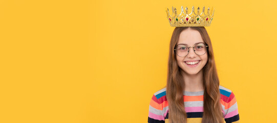 happy child in glasses wear queen crown on yellow background, victory. Child queen princess in crown horizontal poster design. Banner header, copy space. © Olena