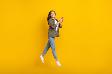 Fototapeta na wymiar Full length photo of young influencer vietnamese jump air businesswoman hold phone remote work freelancer isolated on yellow color background