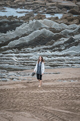 Girl walks on the Itzurun Beach in Zumaia, Basque Country, Spain. Flysh rocks.