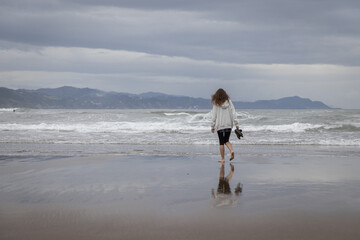 Girl walks on the Itzurun Beach in Zumaia, Basque Country, Spain.