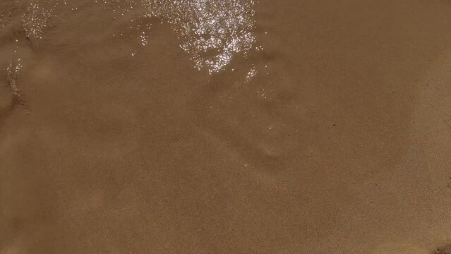 A drawing of a heart on a beach washed away by a wave. Sunny summer day on a beach with love signs taken by the water. Romantic shot.