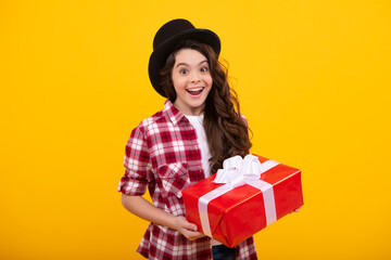 Amazed teenager. Teenager child holding gift box on yellow isolated background. Gift for kids birthday. Christmas or New Year present box. Excited teen girl.