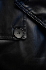 Close-up of a black button on a leather coat. Button on leather fabric