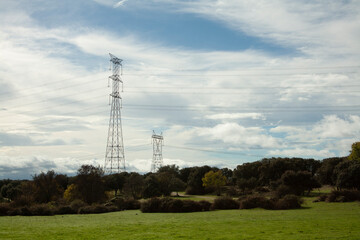 Electric post high voltage tower located along the field until its cables reach the city where it transports its energy