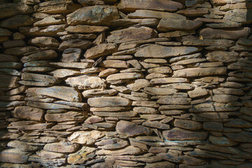 Ripped rustic stone wall in brown tones. Arbitrary stone wall as background or texture.