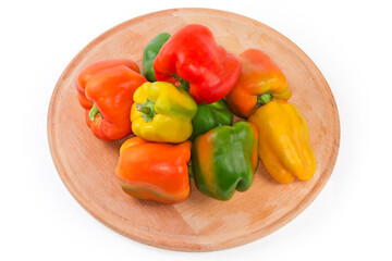 Multicolored bell peppers on the round wooden serving board