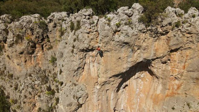 aerial slow motion footage from drone of man rock climber hanging on rope and going down after successful ascent of challenging route on limestone cliff. Geyikbayiri, Turkey. 4k footage