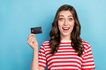 Fototapeta premium Photo of astonished funny lady customer wear striped stylish clothes showing plastic card recommend use isolated on blue color background