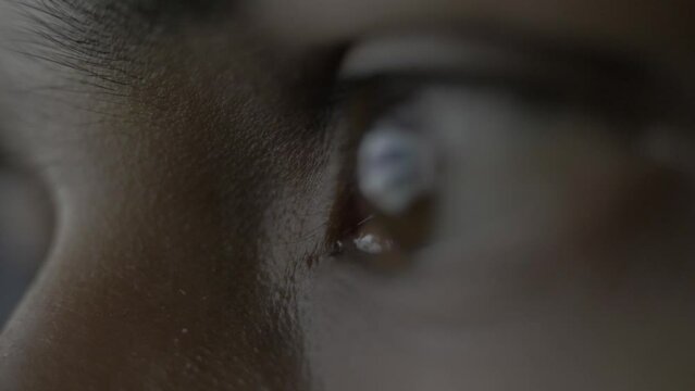 Super extreme close up of a female human eye reflecting a desktop screen while doom scrolling or doom surfing on the web putting unhealthy strain on the eyes