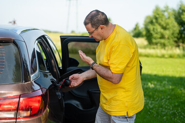 worried and emotional man at open car fuel tank, fuel price rise concept