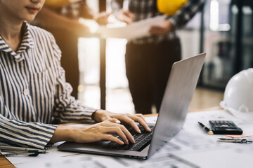Business woman hand working and laptop with on architectural project at construction site at desk in office.