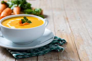 Carrot soup with cream and parsley on wooden table. Copy space
