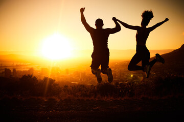 Sunset silhouette, couple jumping and a nature hike adventure for winning fitness exercise, fun...