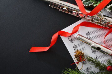 Metal flute on black table Christmas decoration and music sheet © Davizro Photography