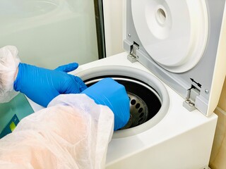 Technician loading a sample to centrifuge machine in the medical or scientific laboratory