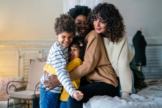 Happy multiethnic family. Smiling gay women couple spending time together with children at home.